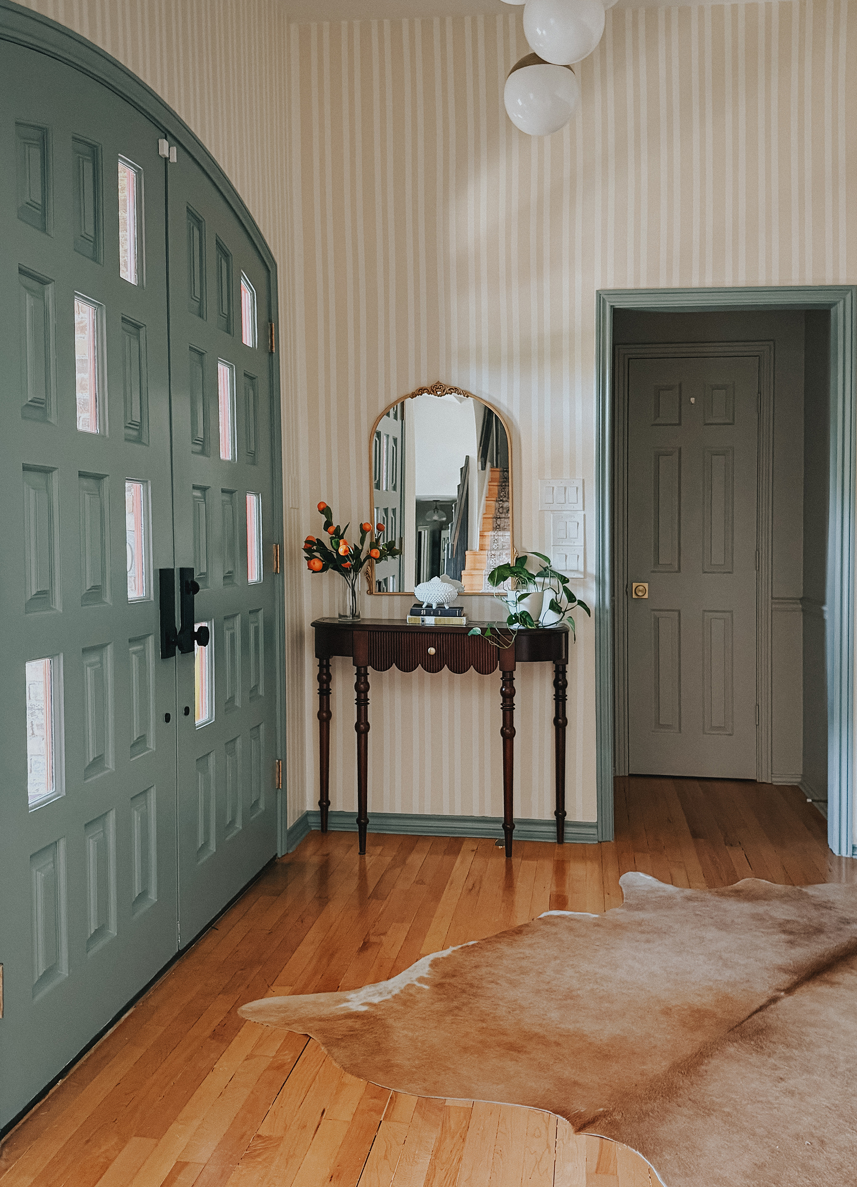 Finished entryway makeover with striped walls, vintage decor, and warm collected style