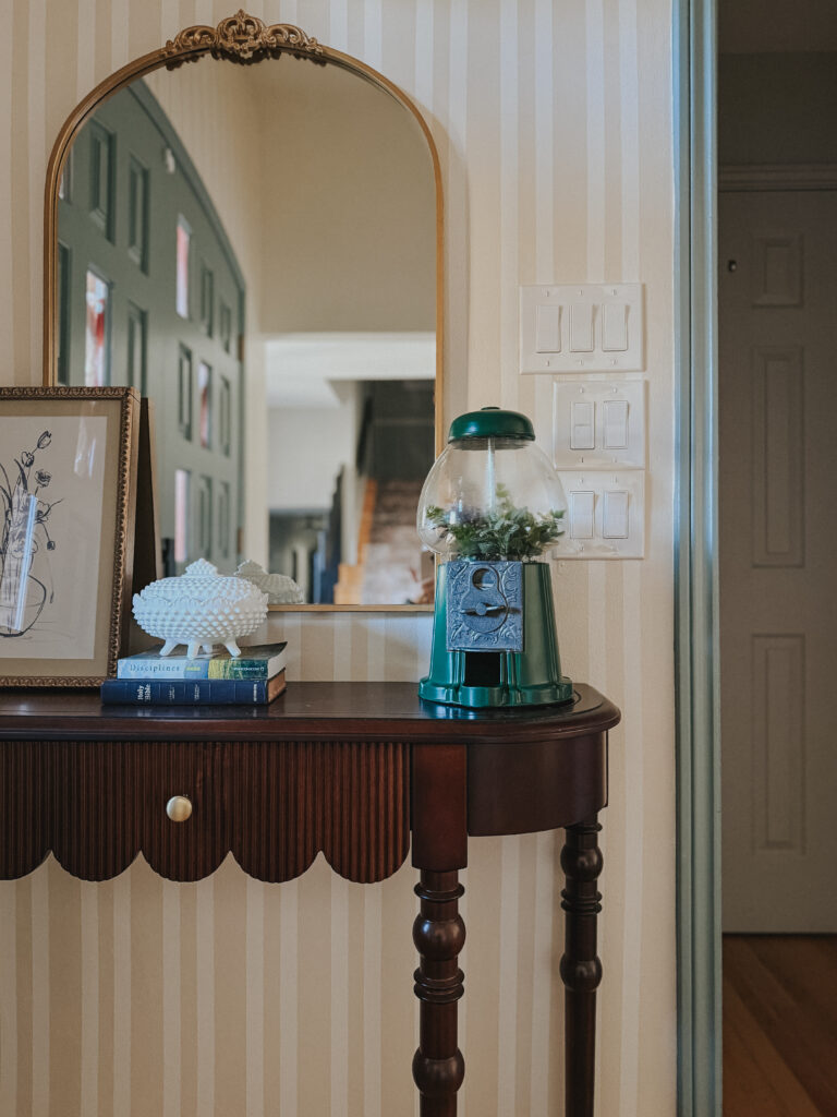 Vintage entry table featuring a DIY gumball machine terrarium and meaningful collected decor